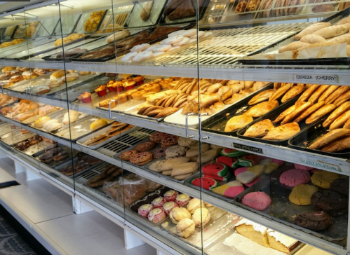 A display case filled with a variety of colorful pastries and baked goods, including cookies and sweet breads.