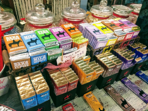 A colorful display of various chocolate bars and treats in jars, arranged neatly on a wooden table.
