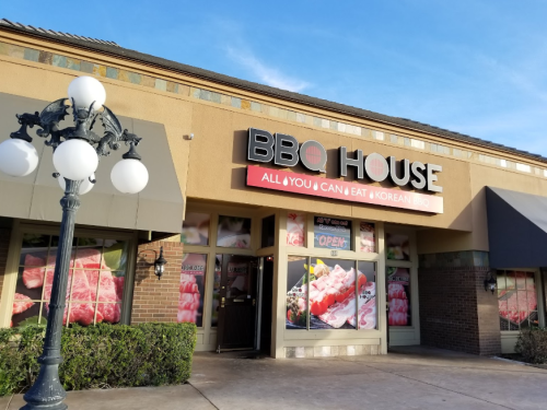 Exterior of BBQ House restaurant featuring "All You Can Eat Korean BBQ" sign and large windows displaying meat options.