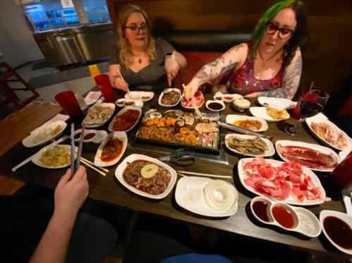 Two women enjoy a feast of various dishes at a table, surrounded by plates of food and drinks.