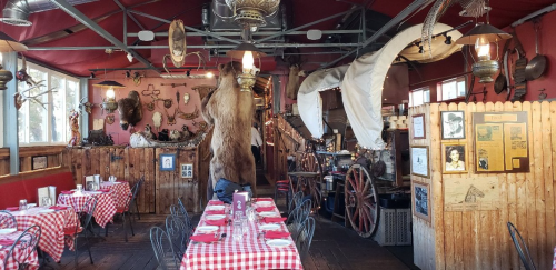 Cozy restaurant interior with checkered tablecloths, rustic decor, and vintage items, creating a warm, inviting atmosphere.