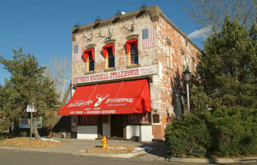 Historic brick building with red awnings, flags, and antlers, featuring "Dawson's Colonial Exchange" signage.