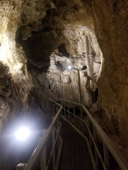 A dimly lit cave interior with a wooden walkway and illuminated rock formations.