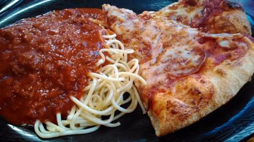 A plate featuring a slice of pizza and a serving of spaghetti with marinara sauce.