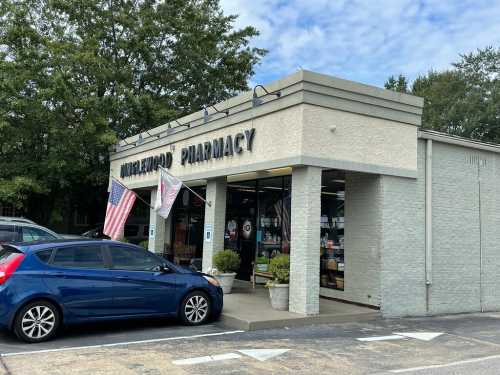 Exterior of a pharmacy with a sign reading "Henderson's Pharmacy," featuring flags and a parked car in front.