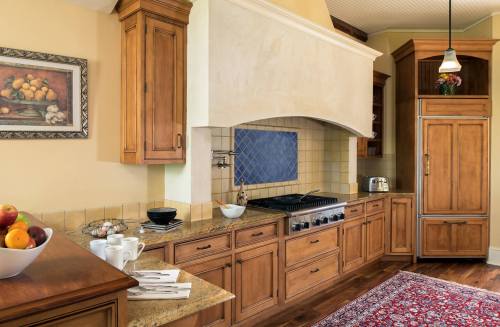 A warm, inviting kitchen with wooden cabinets, a large stove, and a decorative rug on the floor.