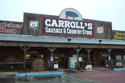 Exterior of Carroll's Sausage & Country Store, featuring a wooden facade and signage, with a parking area in front.