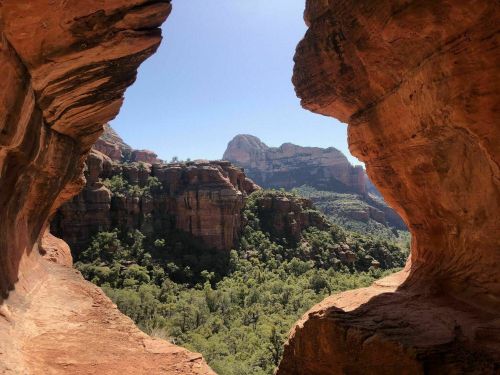 A view of a lush green valley framed by two rocky arches under a clear blue sky.