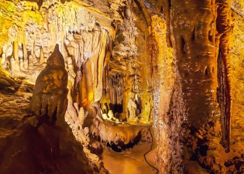 A stunning cave interior with illuminated stalactites and stalagmites, showcasing natural rock formations and textures.