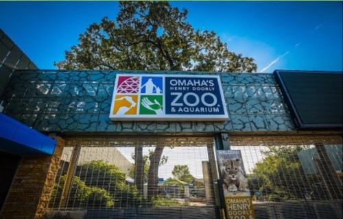 Entrance to Omaha's Henry Doorly Zoo & Aquarium, featuring a colorful sign and a clear blue sky.