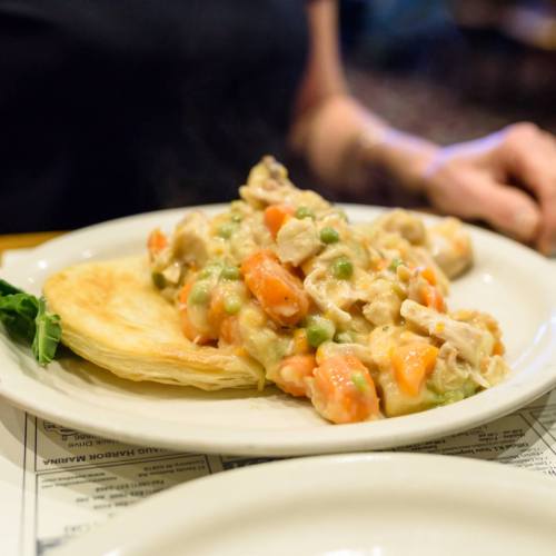 A plate of chicken pot pie filling with vegetables served on a flaky pastry crust.