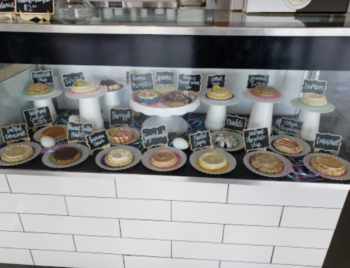 A display case filled with various colorful desserts, each labeled with a small chalkboard sign.
