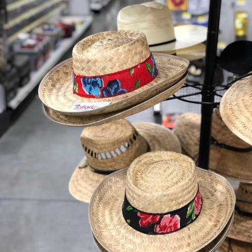 A display of straw hats with colorful floral bands in a store aisle.