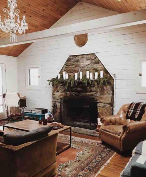 Cozy living room with a stone fireplace, wooden ceiling, and comfortable seating, decorated for a warm atmosphere.