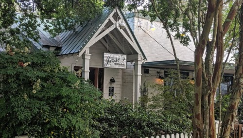 A charming restaurant with a sign reading "Jase's," surrounded by greenery and trees.