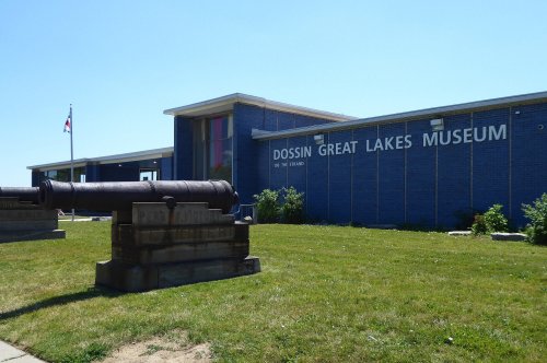 Exterior view of the Dossin Great Lakes Museum, featuring a cannon and a clear blue sky.