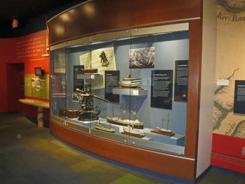 Display case featuring various ship models and historical maritime artifacts in a museum setting.