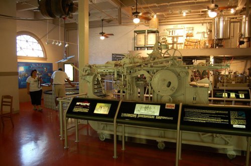 A vintage machine displayed in a museum, with informational panels and visitors exploring the exhibit.