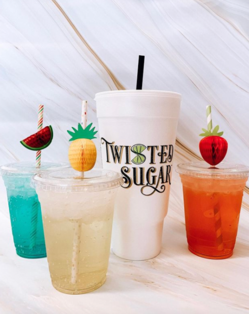 Four colorful drinks with fun fruit-themed straws, including a large cup labeled "Twisted Sugar."