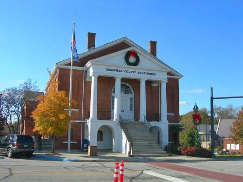Edgefield County Courthouse with festive wreaths, steps leading to the entrance, and a clear blue sky.