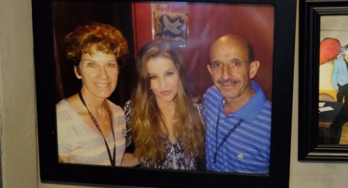 A framed photo of three people smiling together, with a red background and a star decoration.