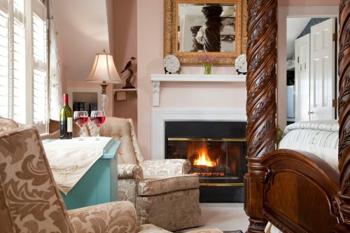 Cozy room with a fireplace, two wine glasses, and elegant armchairs, reflecting a warm and inviting atmosphere.