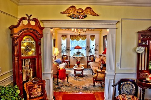 A cozy, elegantly decorated living room with vintage furniture, a chandelier, and an ornate clock.