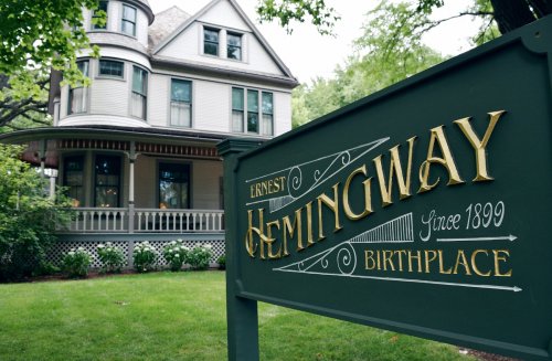 Sign for Ernest Hemingway's birthplace, featuring a historic house in the background surrounded by greenery.