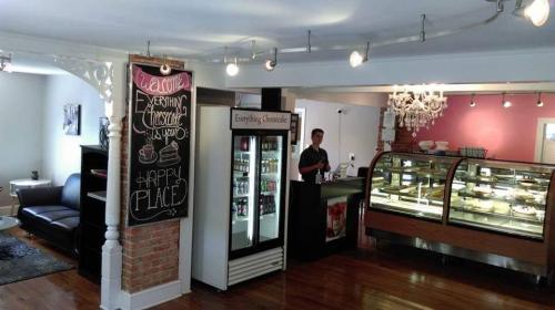 A cozy café interior with a display case of desserts, a chalkboard menu, and a barista behind the counter.