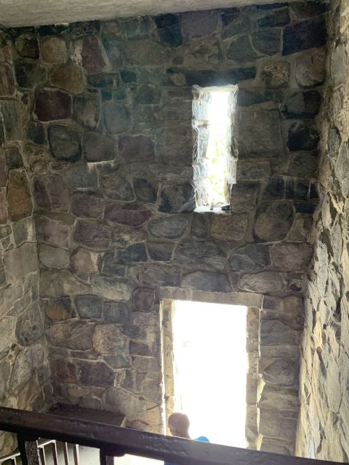 A stone staircase with two small windows letting in light, creating a bright contrast against the dark walls.