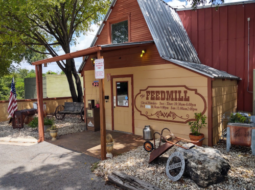 A quaint feed mill building with a welcoming entrance, surrounded by greenery and rustic decor.