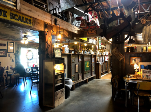 Cozy rustic restaurant interior with wooden decor, vintage items, and warm lighting, featuring a dining area and memorabilia.