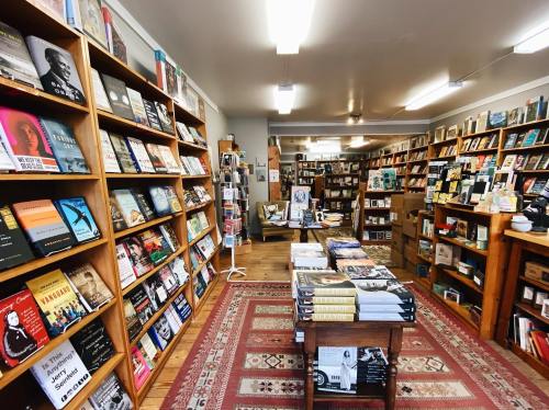 A cozy bookstore interior with wooden shelves filled with books and a central table displaying more titles.