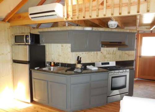 Cozy kitchen with gray cabinets, stainless steel appliances, and wooden accents in a rustic setting.