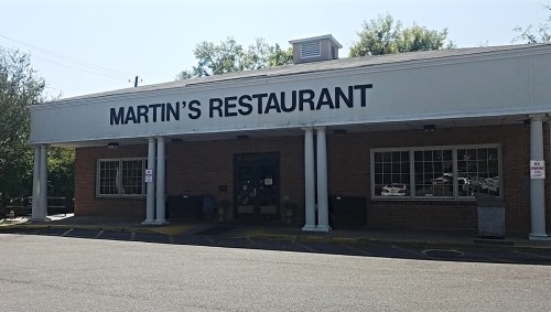 Exterior of Martin's Restaurant, featuring a large sign, white columns, and a brick facade under a clear blue sky.