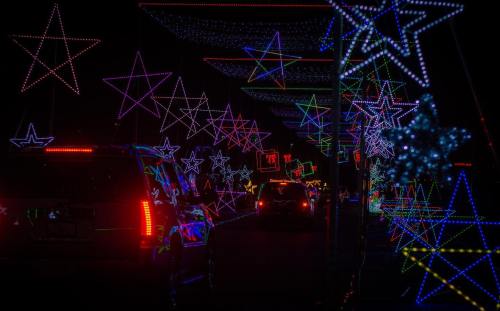 Colorful star-shaped lights illuminate a dark pathway, creating a festive atmosphere for vehicles passing through.