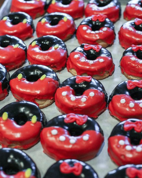 A tray of colorful donuts decorated in red and black, resembling a playful Minnie Mouse theme.