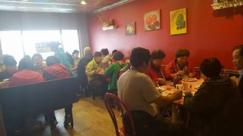 A busy restaurant interior with diners at tables, enjoying meals in a cozy, colorful setting.