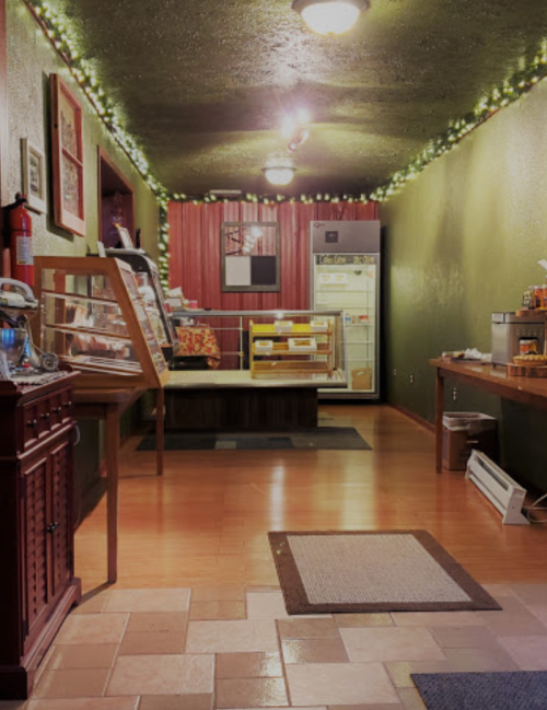 Cozy hallway with green walls, warm lighting, and a display case, leading to a kitchen area.