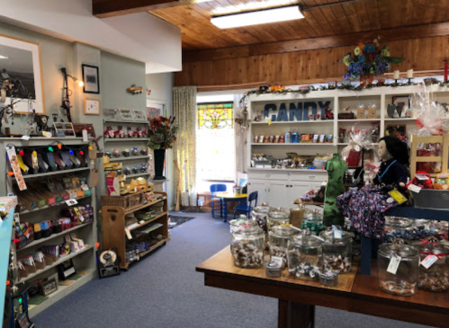 A cozy shop interior filled with shelves of candy, jars of treats, and decorative items, creating a charming atmosphere.
