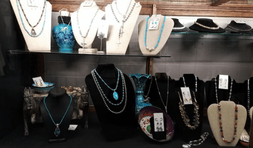 A display of various jewelry pieces, including necklaces and earrings, on stands and in decorative bowls.