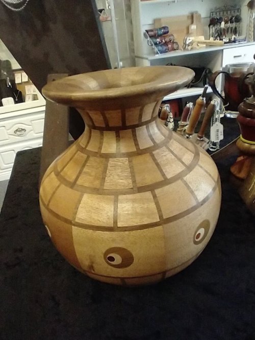 A decorative wooden vase with a wide mouth, featuring geometric patterns and two circular designs on the body.