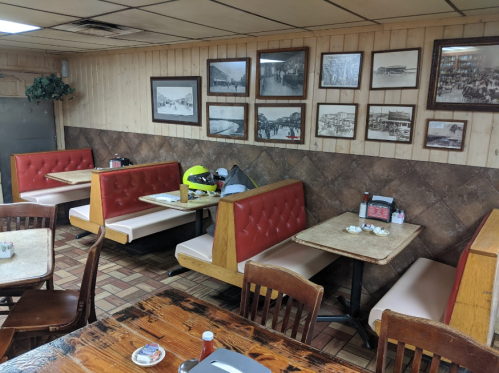 Cozy diner interior with red booths, wooden tables, and vintage photos on the wall.