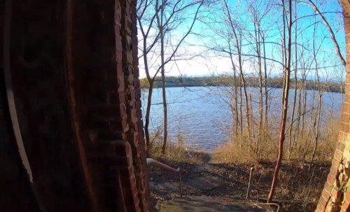 View from a doorway showing a river and trees under a clear blue sky.