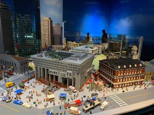 A detailed LEGO cityscape featuring buildings, vehicles, and miniature people in an urban setting.