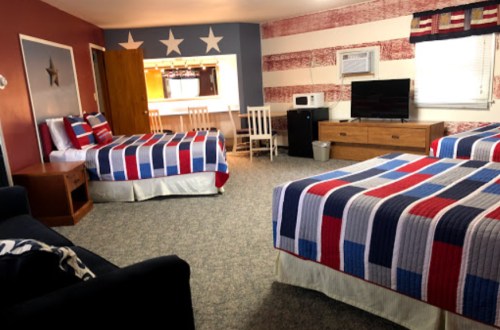 A cozy room with two beds, patriotic decor, a TV, and a small kitchenette area.