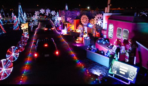 A festive display of colorful lights and decorations, featuring trees, snowflakes, and holiday-themed figures at night.