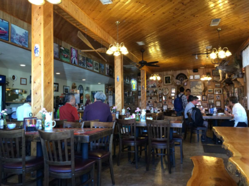 Cozy restaurant interior with wooden decor, tables set for dining, and patrons enjoying their meals.