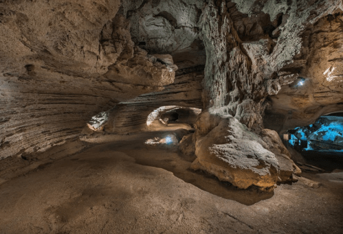 A spacious cave interior with textured rock formations and soft blue lighting illuminating the surroundings.