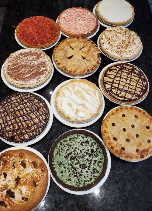 A variety of 15 different pies displayed on white plates, featuring various toppings and crust designs.